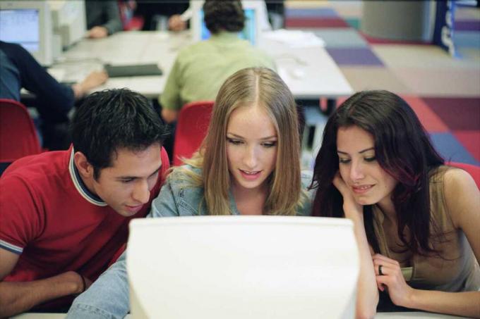 Tres estudiantes at la la pantalla de una computadora.