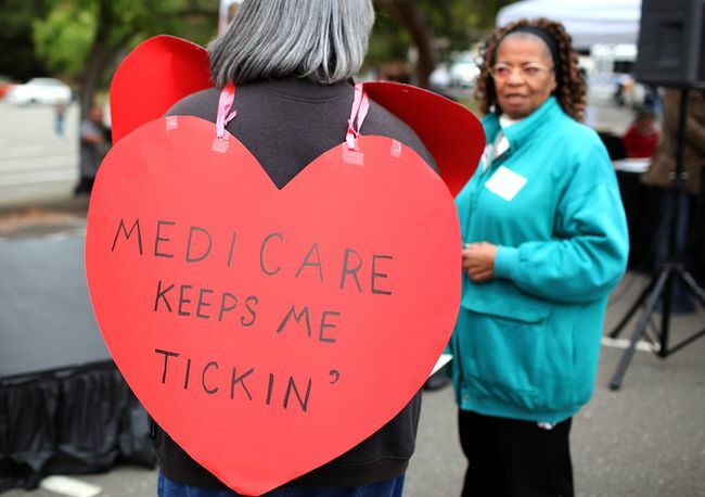 Kalp şeklinde bir tabela takan kadın, 'Medicare Beni İşliyor' yazıyor