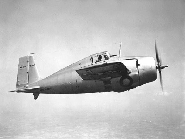 Grumman XF4F-3 Wildcat soldan sağa uçan, gümüş alüminyum kaplama, pilot bakıyor.