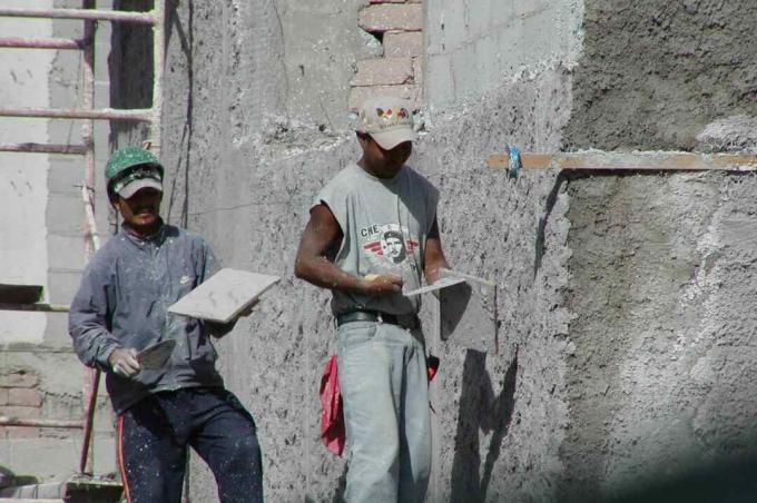 iki işçi, mala ile sıva tabakası uygulayarak